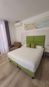Schlafzimmer mit einem großen Bett mit einem grünen Kopfteil in der Unterkunft Affittacamere 5 Terre Dolci Sogni in La Spezia