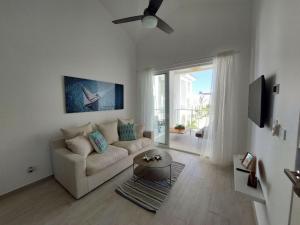 uma sala de estar branca com um sofá e uma janela em Cozy 1BDR with Pool Golf View in Hard Rock Golf em Punta Cana