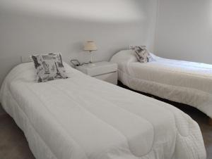 1 dormitorio con 2 camas y una lámpara en una mesa en Quilimbai Departamentos Turísticos en Malargüe