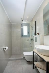 La salle de bains blanche est pourvue d'un lavabo et d'une douche. dans l'établissement Aetheria Central Apartments, à Rhodes