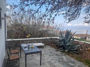 un patio con mesa, sillas y pared de piedra. en Maison charmante en Hydra