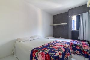 a bedroom with a bed with a floral blanket on it at Apt/Cas Porto de Galinhas in Porto De Galinhas