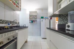 a kitchen with white appliances and black counter tops at Apt/Cas Porto de Galinhas in Porto De Galinhas