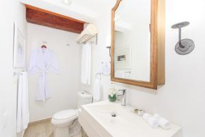 a white bathroom with a robe hanging on the wall at Hotel Boutique Casa del Coliseo in Cartagena de Indias