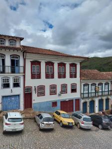 un grupo de autos estacionados en un estacionamiento frente a un edificio en República Birinaite, en Ouro Preto