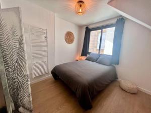 een slaapkamer met een bed in een kamer met een raam bij Casa Bondy - Sublime T2 Refait à Neuf - Hyper Centre de Brive in Brive-la-Gaillarde