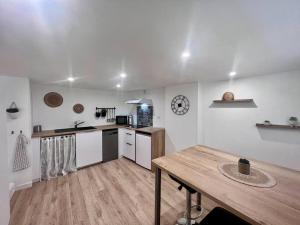een keuken met witte muren en een houten tafel bij Casa Bondy - Sublime T2 Refait à Neuf - Hyper Centre de Brive in Brive-la-Gaillarde