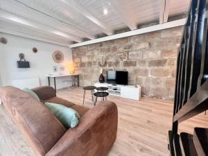 a living room with a couch and a stone wall at Casa Bondy - Sublime T2 Refait à Neuf - Hyper Centre de Brive in Brive-la-Gaillarde
