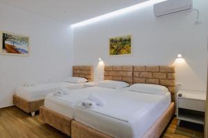 2 Betten in einem Zimmer mit weißen Wänden und Holzböden in der Unterkunft Vila Jon'a in Sarandë