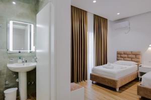 ein Bad mit einem Bett, einem Waschbecken und einem Spiegel in der Unterkunft Vila Jon'a in Sarandë