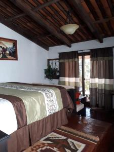 1 dormitorio con 2 camas, mesa y ventanas en Bosque Macadamia, en El Tejar