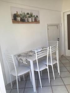 een witte eettafel met witte stoelen en planten bij Casa Nimeca in Palagiano