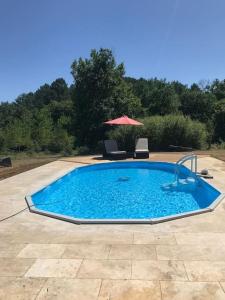 a large swimming pool with an umbrella and two chairs at Peaceful, comfortable retreat with pool in Montcléra