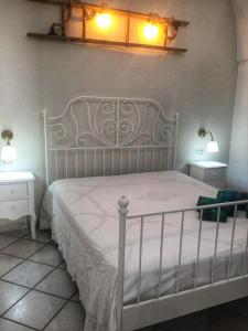 een slaapkamer met een wit bed met 2 nachtkastjes en 2 lampen bij Casa Nimeca in Palagiano