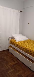 Cama en habitación con paredes blancas y suelo de madera. en Departamento Céntrico 2 dormitorios en San Miguel de Tucumán