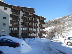 un parking couvert de neige en face d'un bâtiment dans l'établissement Les Melezes, à Saint-Chaffrey