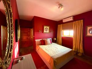 Dormitorio rojo con cama y ventana en Petra Penthouse, en San Lawrenz