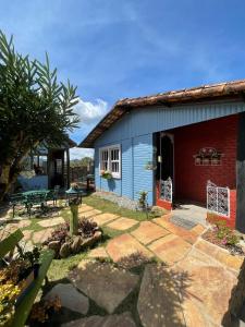 une maison bleue avec un banc et une table dans l'établissement Casa das flores - Lavras Novas, à Lavras Novas