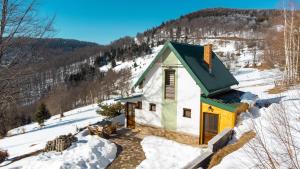 ein kleines Haus mit grünem Dach im Schnee in der Unterkunft Golijski Vuk in Raška