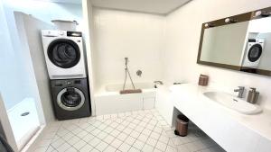uma casa de banho com uma máquina de lavar e secar roupa ao lado de um lavatório em Appartement 3P 88 m2 terrasse et jardin à 20 metres de la plage em Antibes