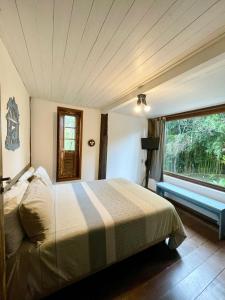 a bedroom with a bed and a large window at Casa das flores - Lavras Novas in Lavras Novas