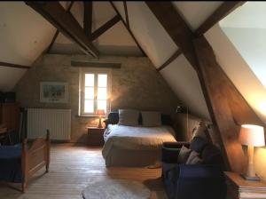 Maison cosy dans village historique في Coucy-le-Château-Auffrique: غرفة نوم بسرير واريكة في العلية