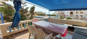 einen Tisch und Stühle auf einem Balkon mit Sonnenschirm in der Unterkunft villa swiriya atlantique in Souira Guedima