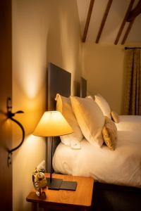 a bed with white pillows and a table with a lamp at All Seasons Cottage Breaks in Saxmundham