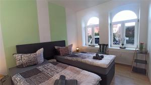 two beds in a room with two windows at Apartment für bis zu 7 Personen mit Balkon in Halberstadt
