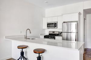 a white kitchen with a stainless steel refrigerator and stools at Jersey City 1BR w Elevator WD quiet street NYC-729 in Jersey City +10 photos