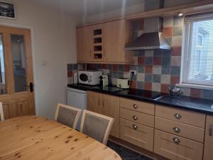 a kitchen with a wooden table and a kitchen with a stove at Swilly Cottage, Portstewart in Portstewart