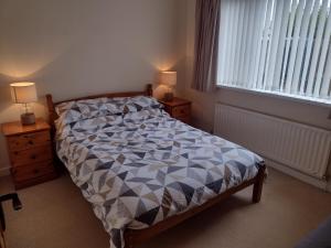 a bedroom with a bed and two night stands and a window at Swilly Cottage, Portstewart in Portstewart