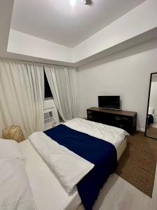 Schlafzimmer mit einem Bett, einem Schreibtisch und einem Fenster in der Unterkunft The Patio at Monaco Tower in Lagundi