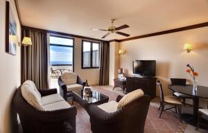 a living room with chairs and a table and a television at Occidental Jand&iacute;a Royal Level - Adults Only in Morro del Jable