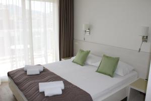 1 dormitorio con 1 cama blanca grande con almohadas verdes en Apartments Lavanda, en Budva