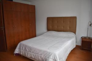 1 dormitorio con cama blanca y armario de madera en Casa Los Acantilados en Mar del Plata
