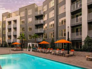 a pool with chairs and umbrellas in front of a building at Milpitas 1BR w Gym Pool nr BART Great Mall SFO-544 in Milpitas