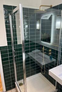 baño de azulejos verdes con ducha y lavamanos en West Loch Farm Bothy, en Peebles