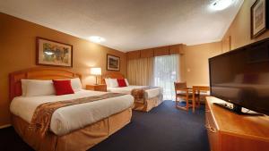 a hotel room with two beds and a flat screen tv at Best Western Inn at Penticton in Penticton