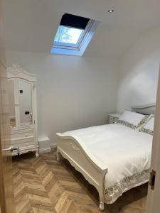 1 dormitorio con cama blanca y ventana en West Loch Farm Bothy, en Peebles