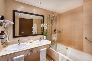 a bathroom with two sinks and a shower and a mirror at NH Collection León Plaza Mayor in León