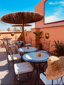 eine Terrasse mit Tischen und Stühlen und einem großen Sonnenschirm in der Unterkunft Riad Allal in Marrakesch