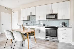 une cuisine avec des armoires blanches et une table et des chaises en bois dans l'établissement San Carlos 2BR w Gym Pool BBQ nr Caltrain SFO-910, à San Carlos