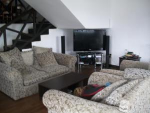 a living room with couches and a flat screen tv at Sherwood Cottage in Nuwara Eliya