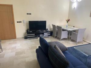 a living room with a couch and a tv and a table at Savannah Beach Sidi Rahal Casablanca in Dar Hamida