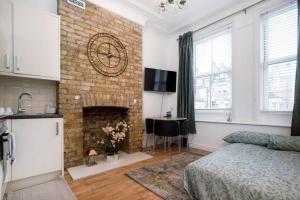 um quarto com uma lareira de tijolos e um relógio na parede em flat in south west London 1 min to the station em Londres