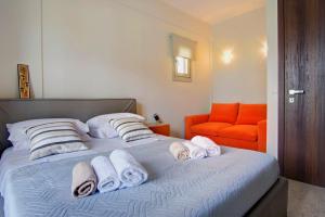 - une chambre avec un lit, des serviettes et une chaise orange dans l'établissement Villa Aurora, à Acharavi