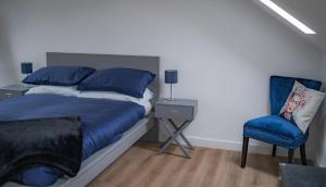 a bedroom with a bed and a blue chair at The Red House- 3 Parking Spaces Walking Distance to City Centre and Cardiff Bay 3 dbl bedrooms in Cardiff