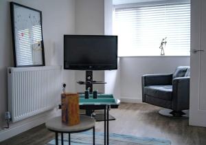 a living room with a tv and a chair and a table at Modern 3-Bed Home with Large Parking Space a Short Walk to Cardiff Bay or City Centre Contractor Friendly" in Cardiff
