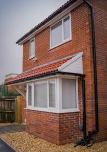 a red brick house with a white window at Modern 3-Bed Home with Large Parking Space a Short Walk to Cardiff Bay or City Centre Contractor Friendly" in Cardiff